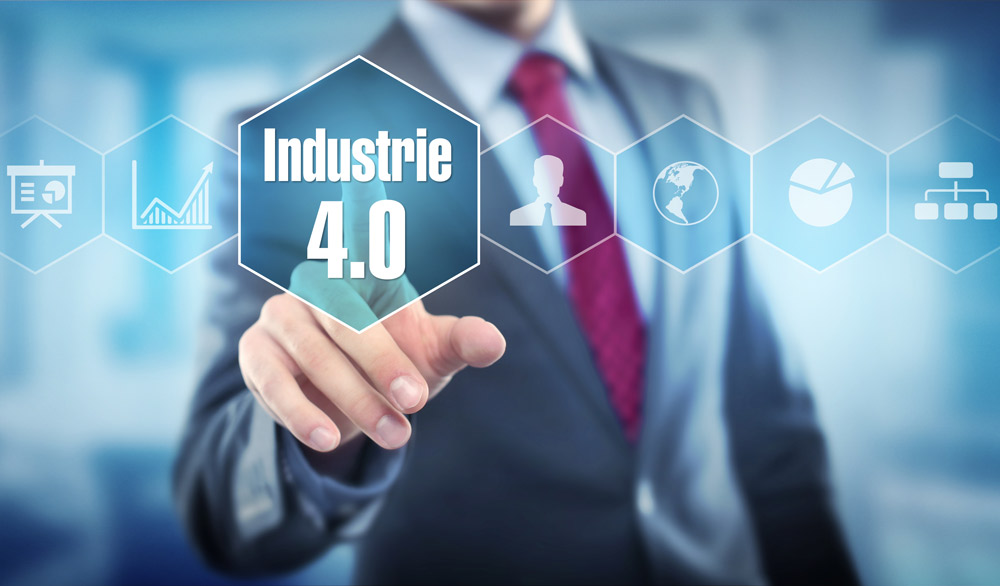 [Translate to english:] Mann im Anzug, der auf Wabe mit Titel dem Titel "Industrie 4.0" zeigt