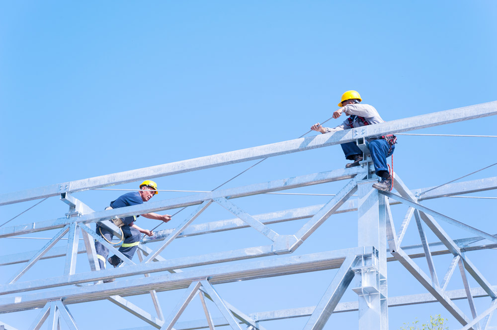 Zwei Menschen, die gesichert auf Stahlgerüst arbeiten